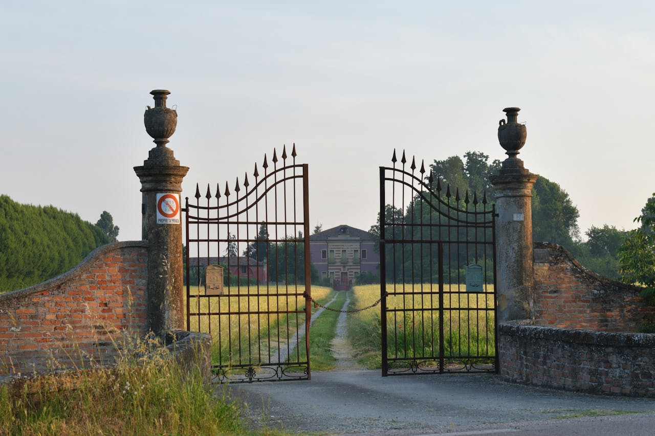 Beautiful wrought iron gate opening to a countryside villa in Veneto, Italy during a summer day.